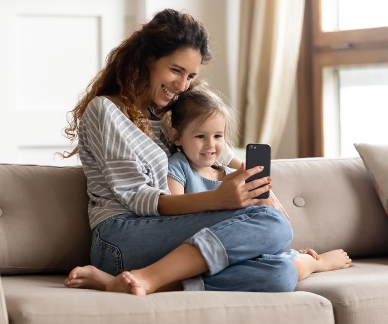 Mamma och barn som ler och tittar i mobilen